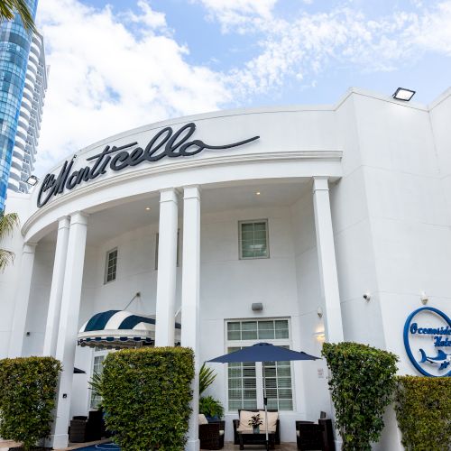 The image shows a white building named "Oceanside Hotel" with a modern style and palm trees in the surroundings.