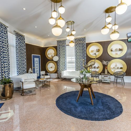A stylish lobby with modern decor features blue-patterned curtains, circular wall displays, a blue rug, and decorative lighting fixtures.