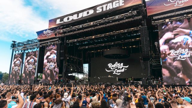 The image shows a large outdoor music festival stage labeled "LOUD STAGE" with a crowd gathered, featuring "Rolling Loud" branding.