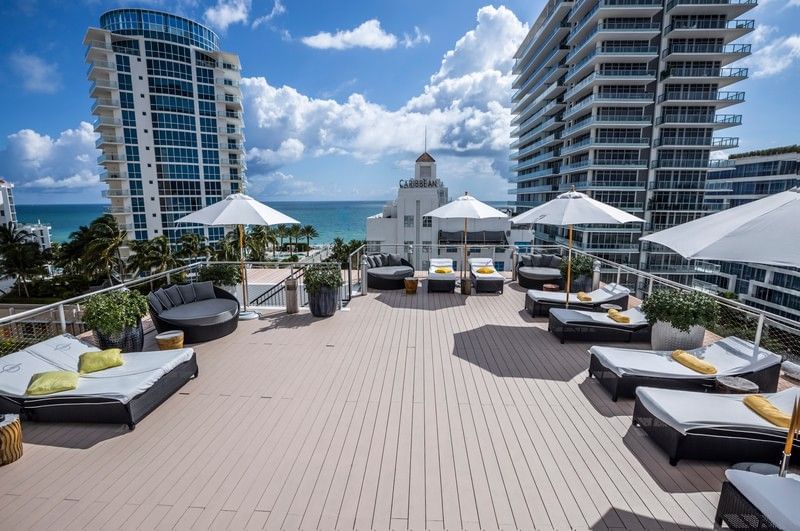 A pool area with sun loungers, parasols and a seaside view.